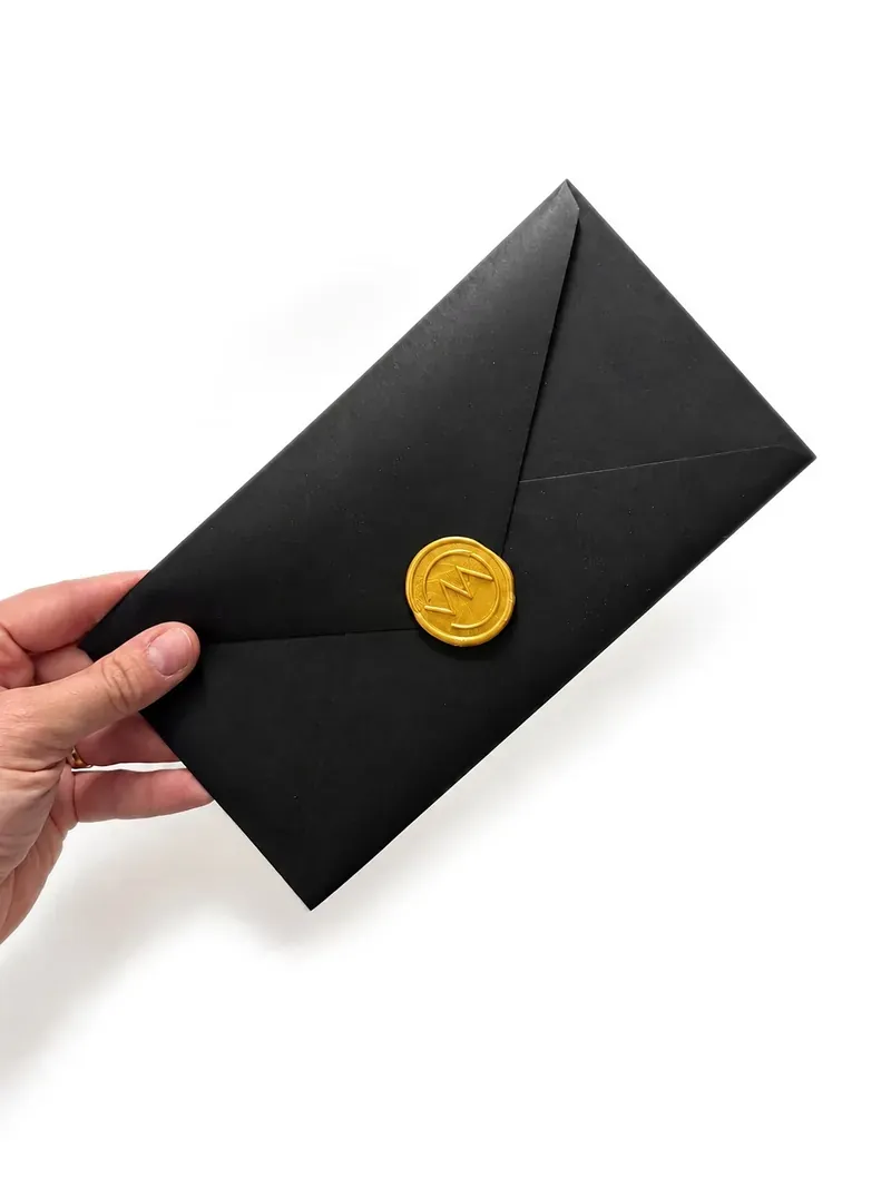 L'enveloppe noire du bon cadeau, scellée d'un cachet doré